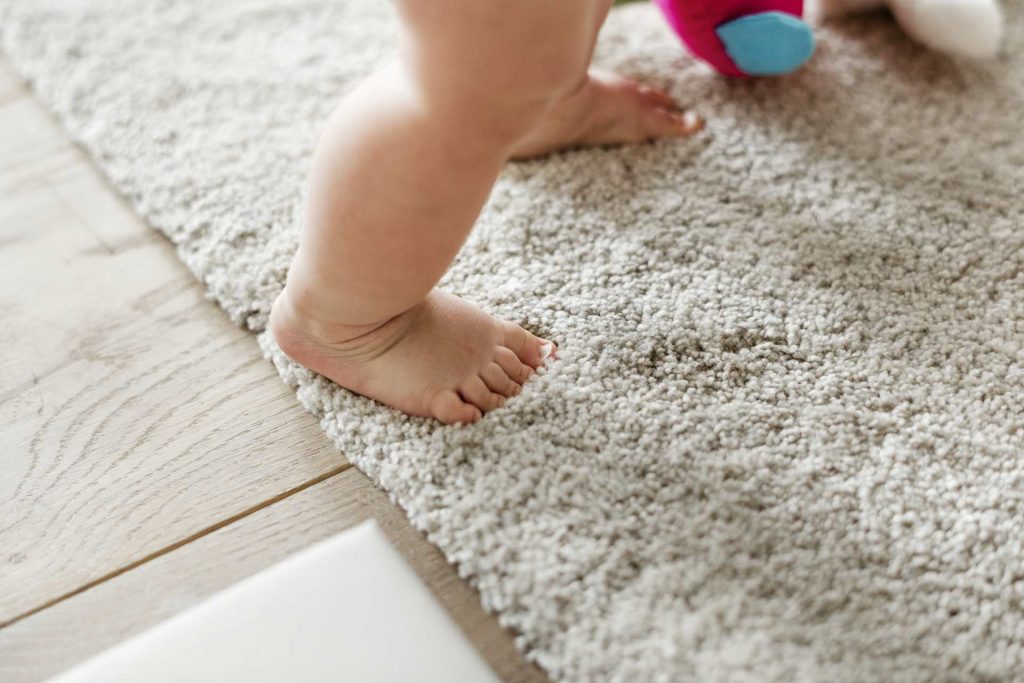 Close-up of a baby's feet while he is standing on a comfy rug.