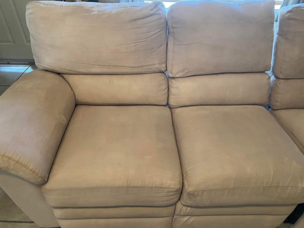 Spotless cream-colored couch in a room, looking fresh and clean after being thoroughly cleaned and restored.