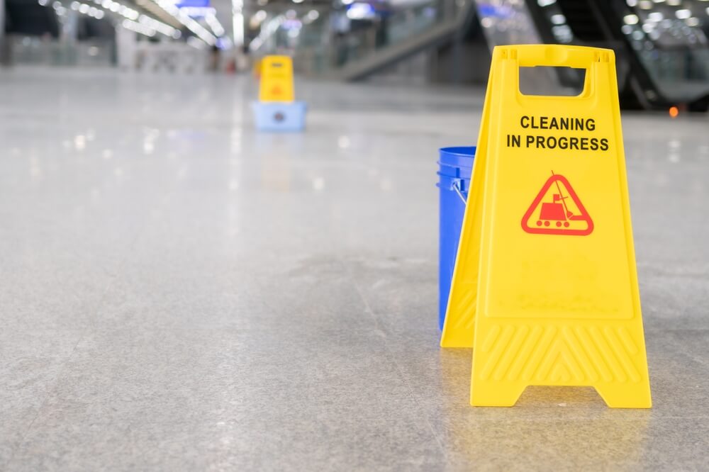 Yellow plastic cone with wet floor warning sign at department store.